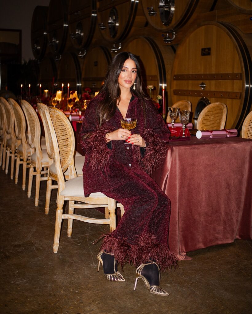 Burgundy evening outfit with feather-trimmed sleeves, matching trousers and metallic heels.