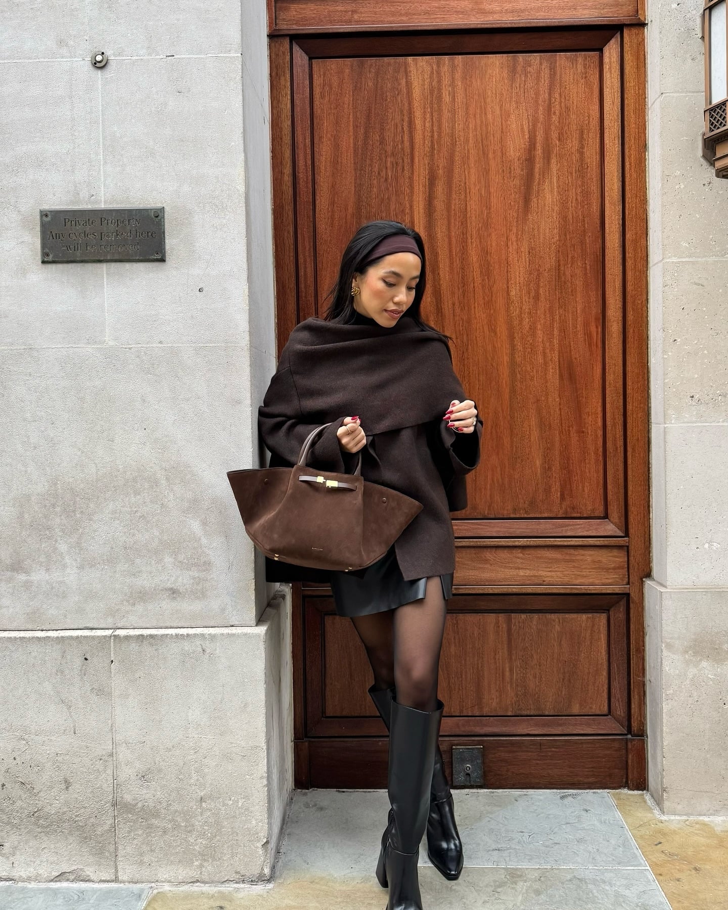 Brown wrap sweater with black leather mini skirt and knee-high boots for a casual Christmas Eve outfit.