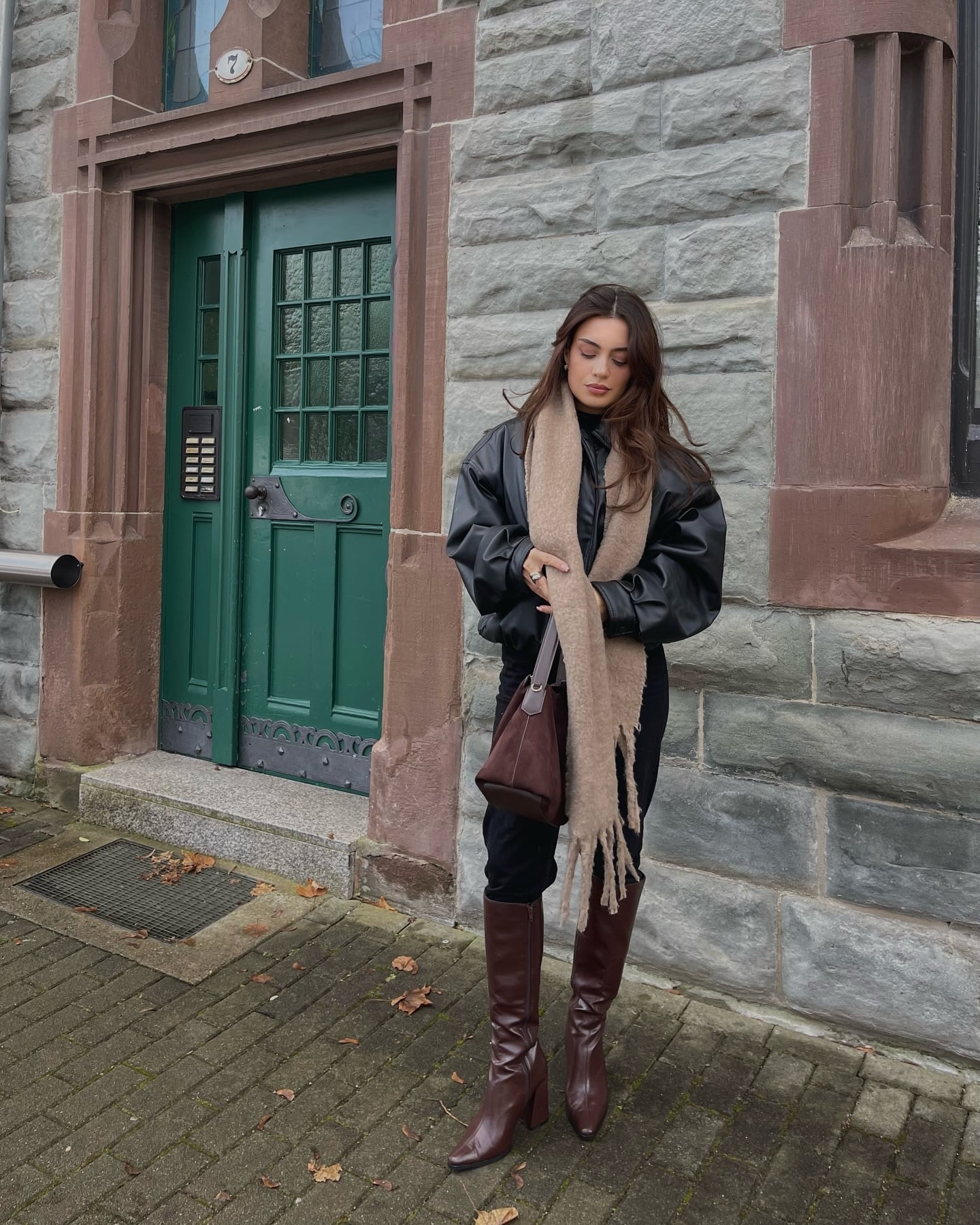 Black leggings outfit with burgundy knee-high heeled boots, black leather jacket, and beige scarf