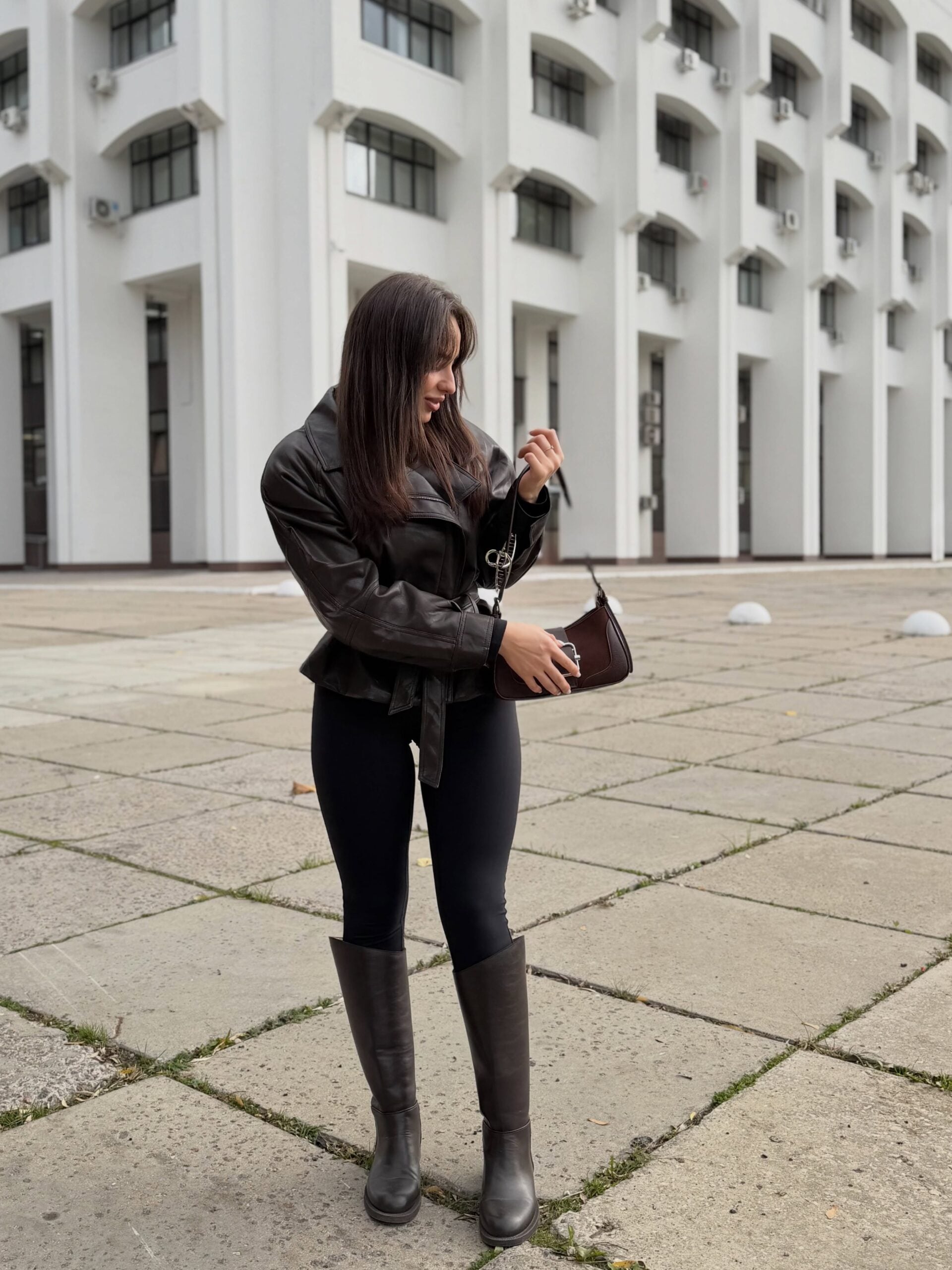 Black leggings with dark brown riding boots, fitted black leather jacket, and brown shoulder bag