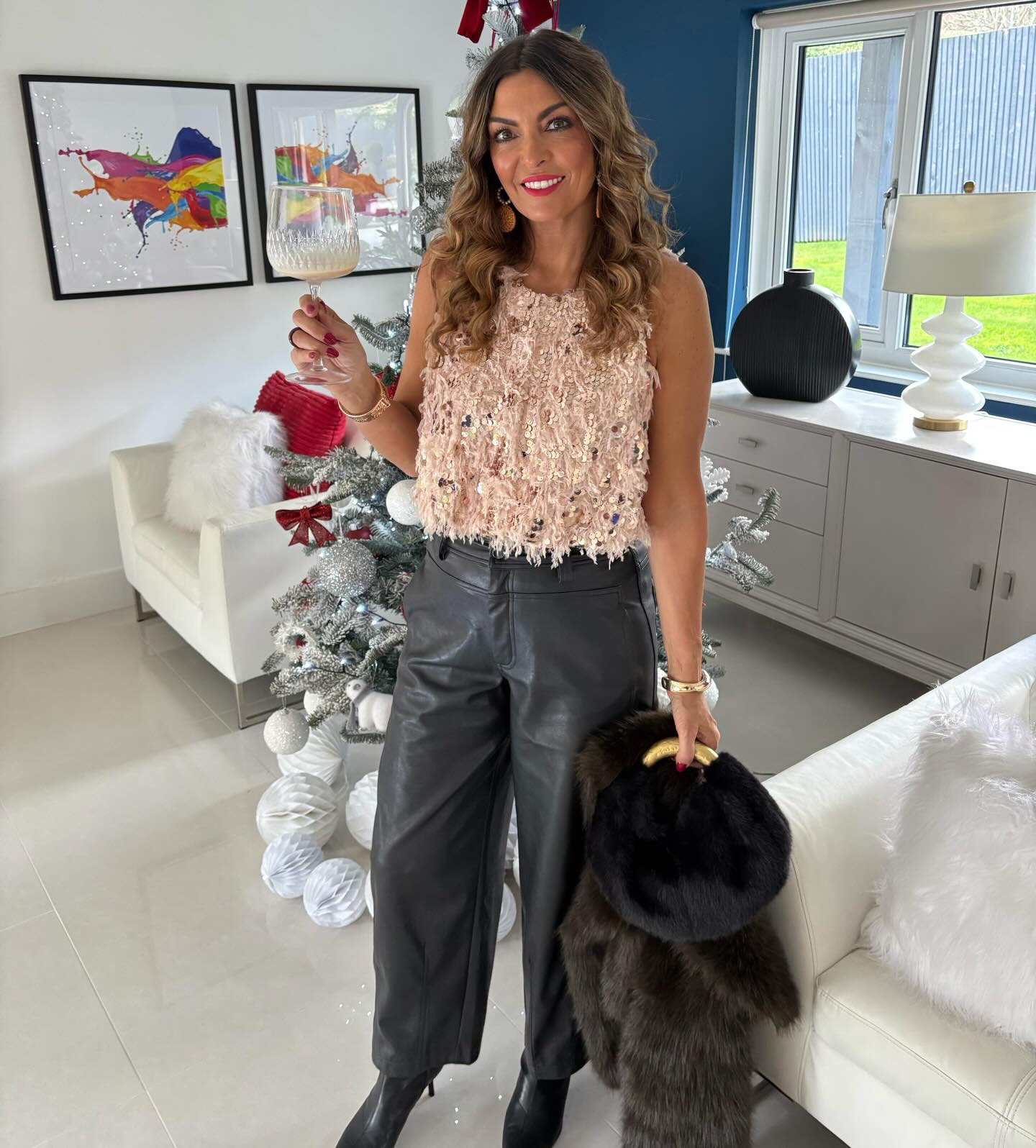 Blush sequin top with black faux leather pants, ankle boots, and a fur coat for a Christmas party outfit