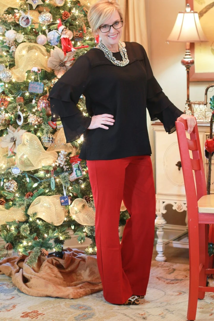 Black ruffle-sleeve top with red wide-leg pants and a statement necklace for a Christmas party