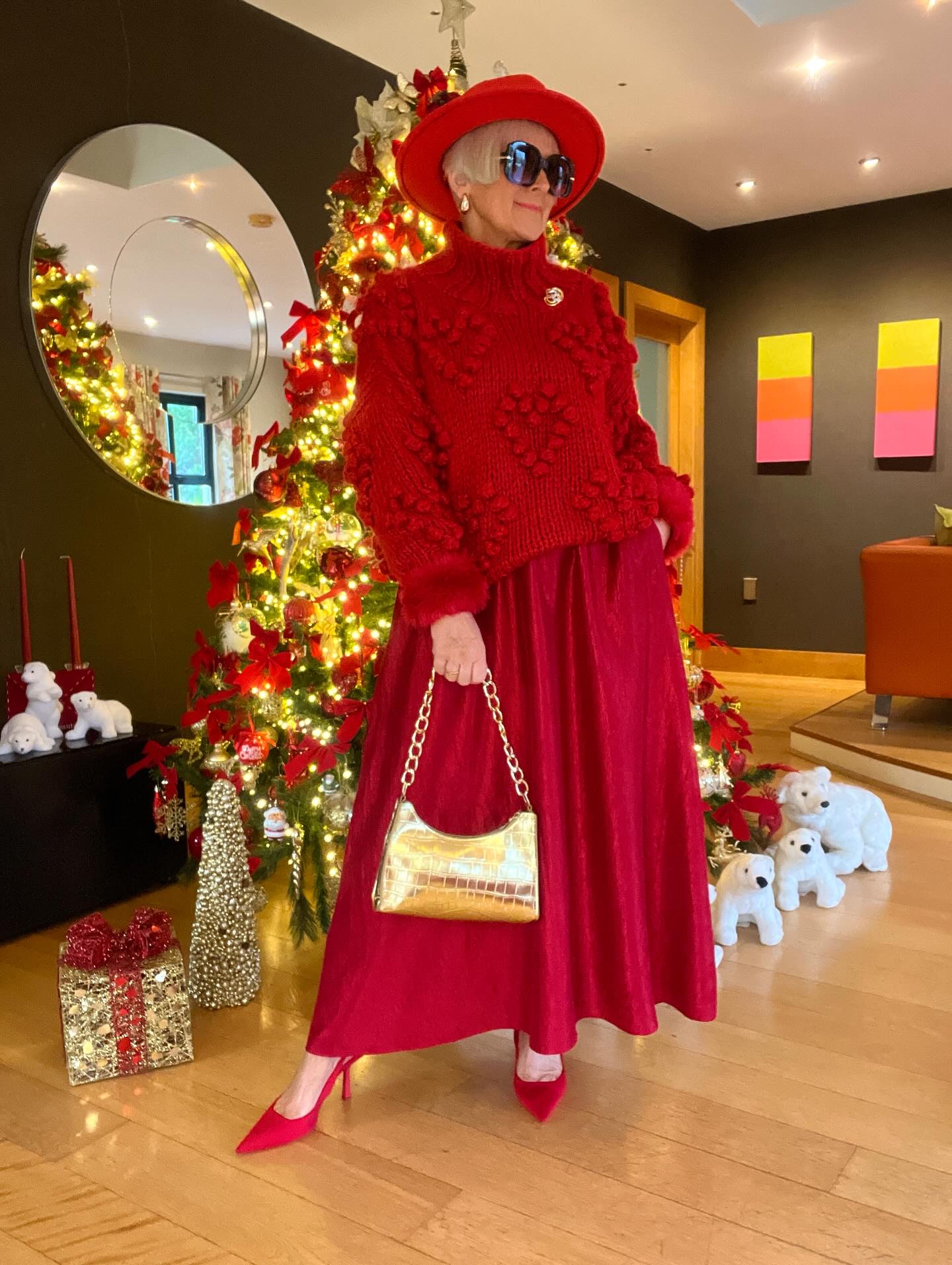 Red textured sweater with a flowing red midi skirt, red shoes, and a gold handbag for Christmas dinner