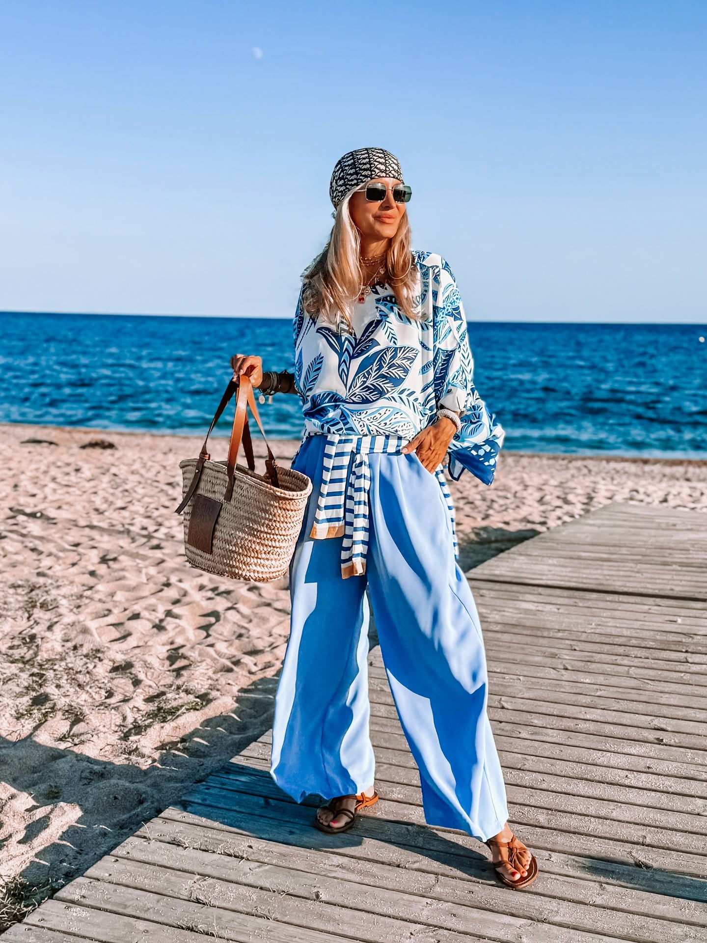 woman over 40 wearing a printed blouse with blue wide-leg trousers