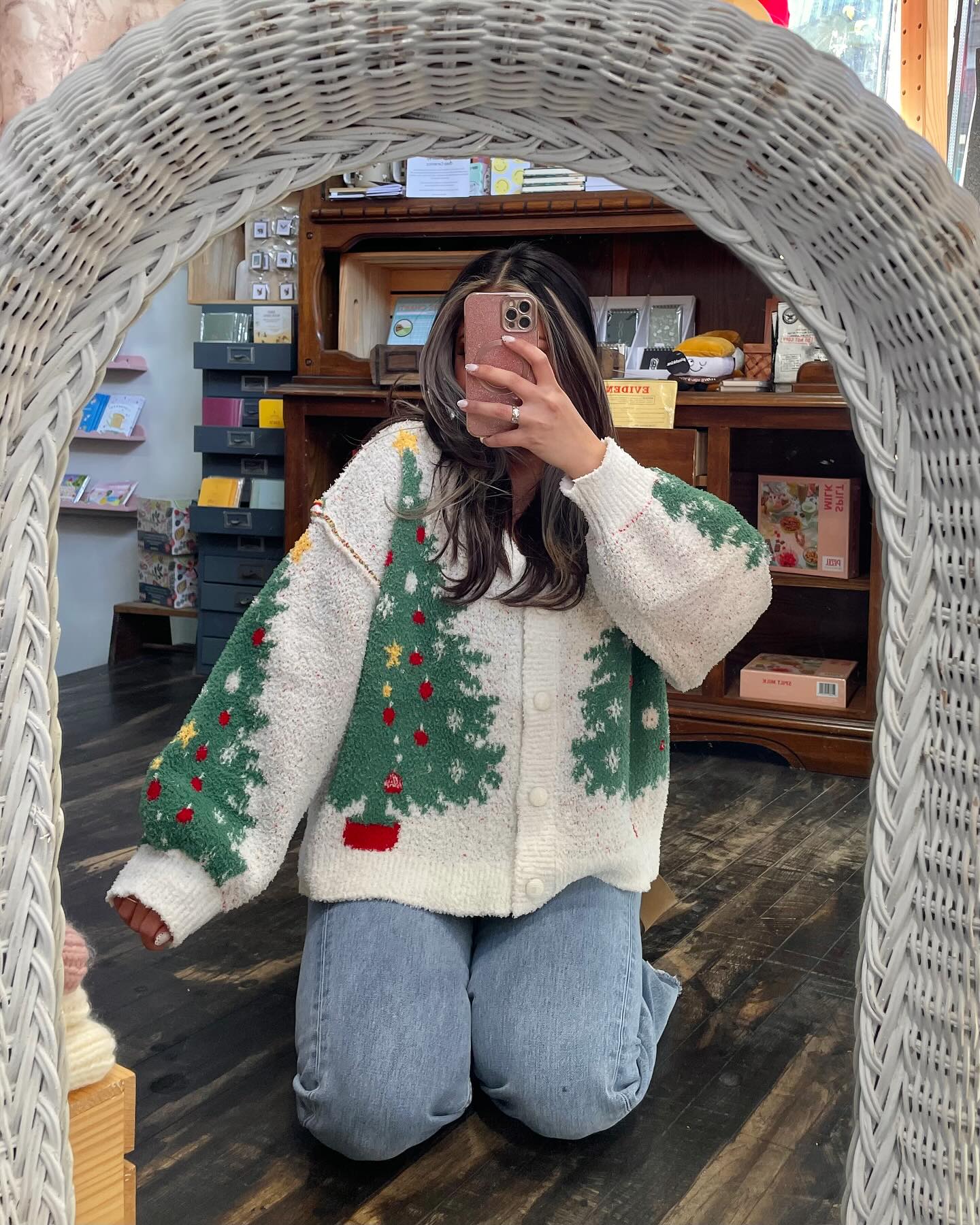 Cute Christmas cardigan outfit with a white Christmas tree knit cardigan and light-wash baggy jeans.