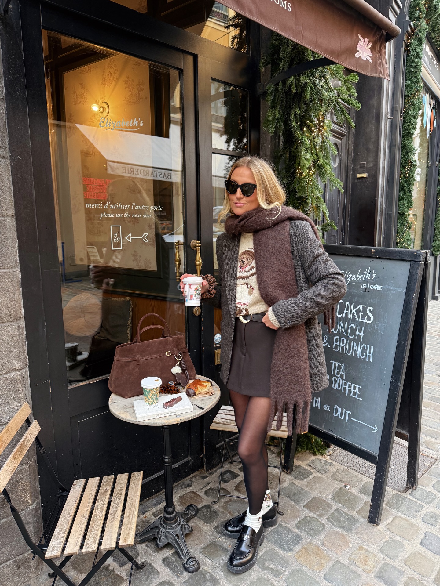 Christmas party sweater outfit with a teddy bear knit, grey oversized blazer, brown mini skirt, sheer tights, and black loafers.
