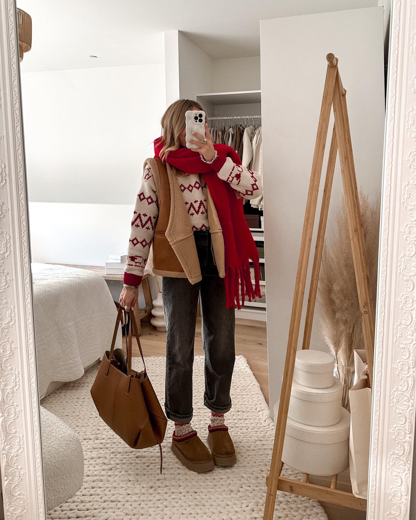 Cozy Christmas outfit with a cream Fair Isle sweater, tan shearling vest, dark jeans, red scarf, and UGG boots.