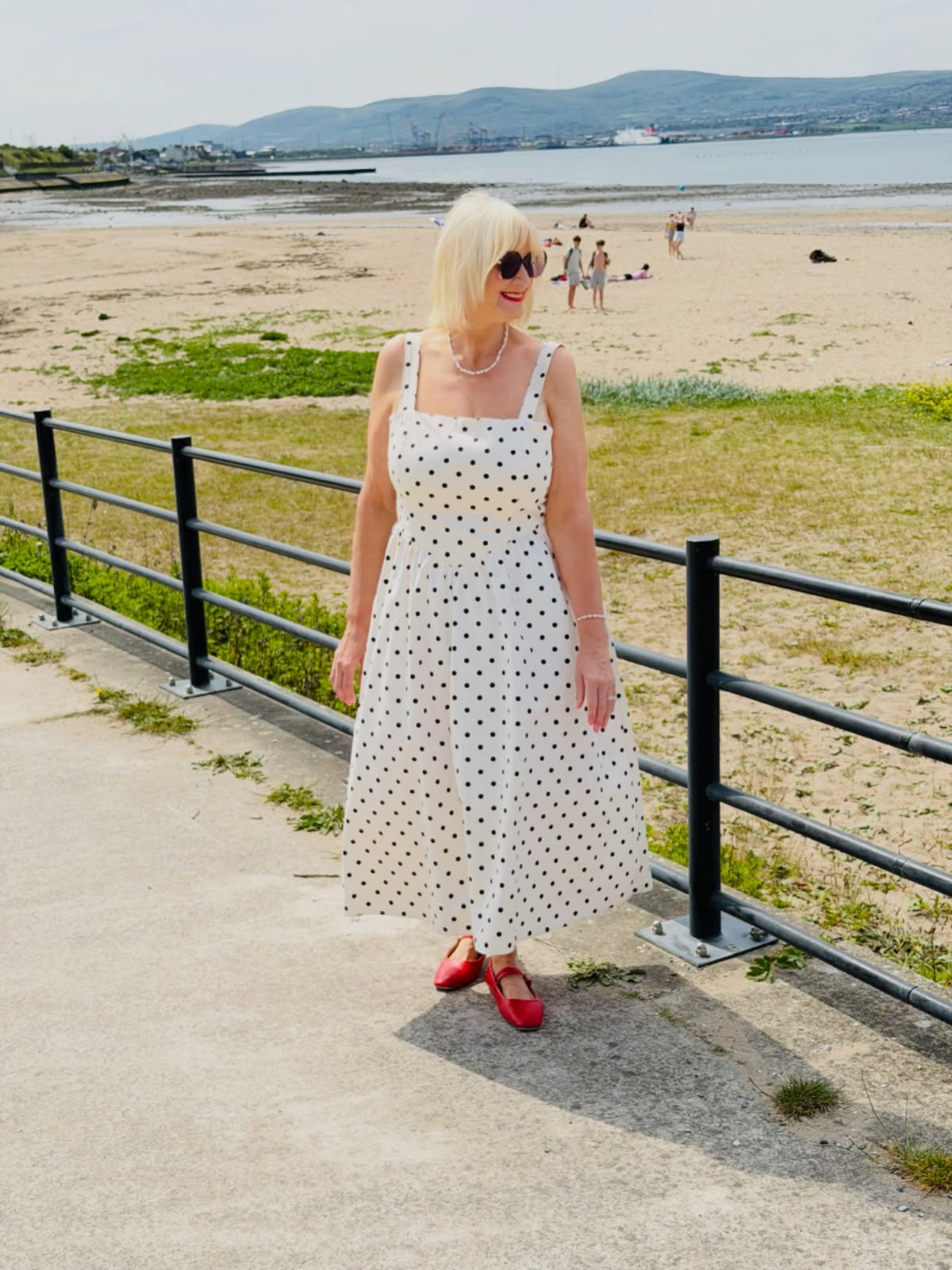 White polka-dot dress with a shaped bodice and full skirt, styled as a dress outfit idea for women over 50.