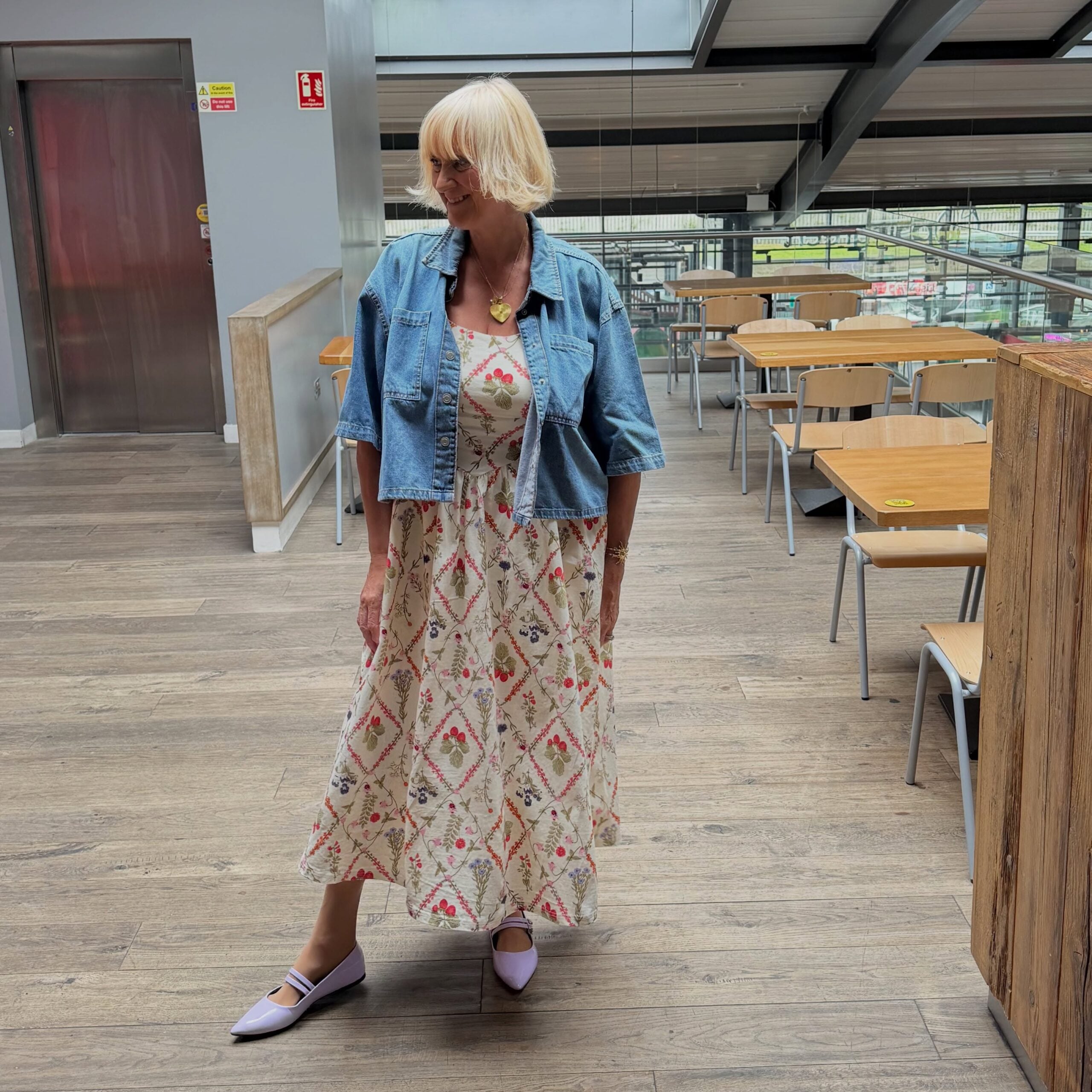 Floral dress with a cropped denim jacket, a casual outfit idea for women over 50.