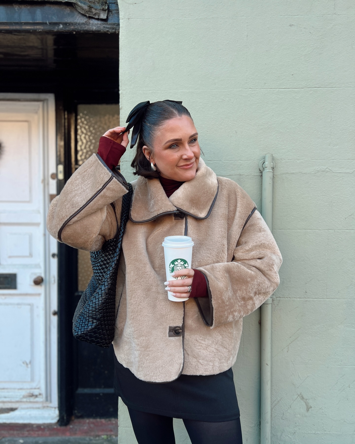 Cold weather fall outfit for women over 40 with teddy jacket, black skirt, tights and ankle boots