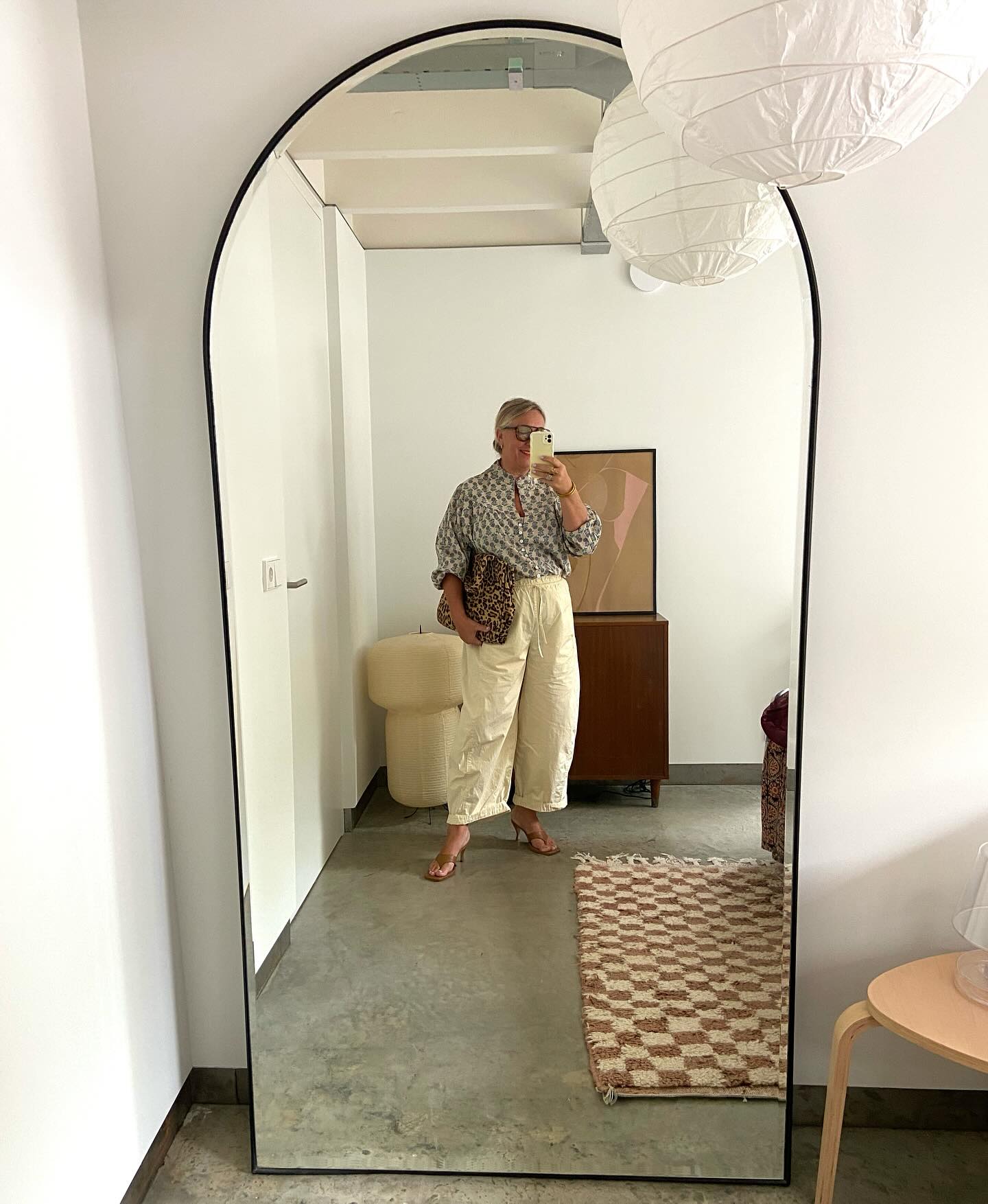 Warm weather fall outfit for women over 40 with printed blouse and relaxed cream trousers