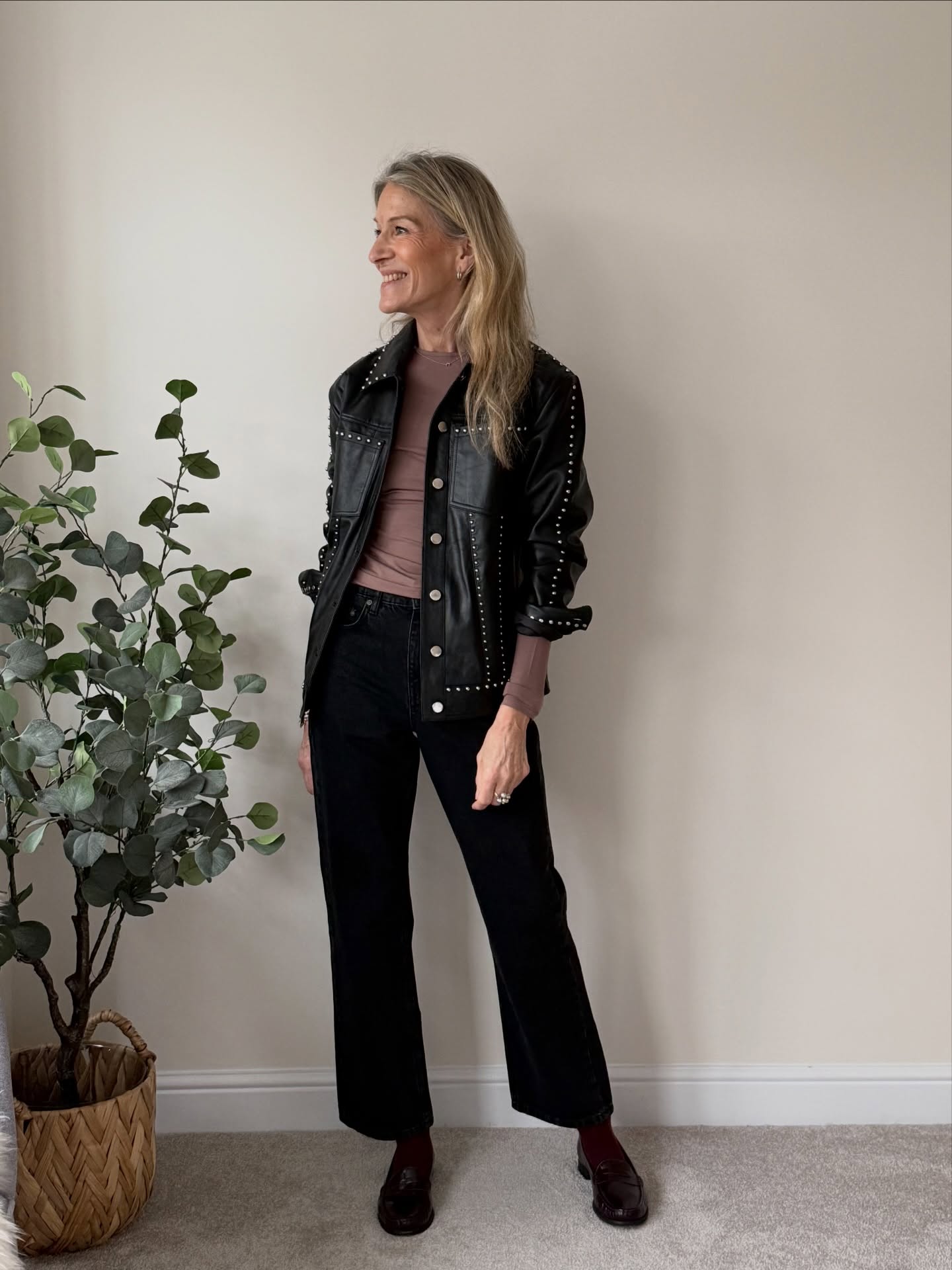 Black jeans fall outfit for women over 40 with leather jacket, knit top and burgundy loafers