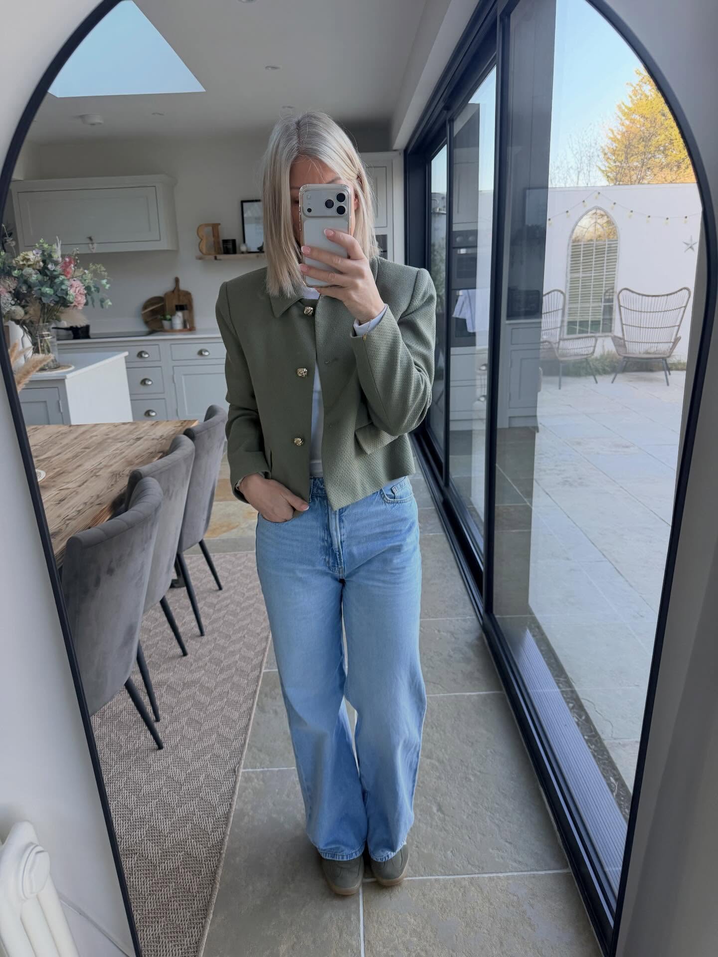 Casual fall jeans outfit for women over 40 with light-wash jeans and cropped green jacket
